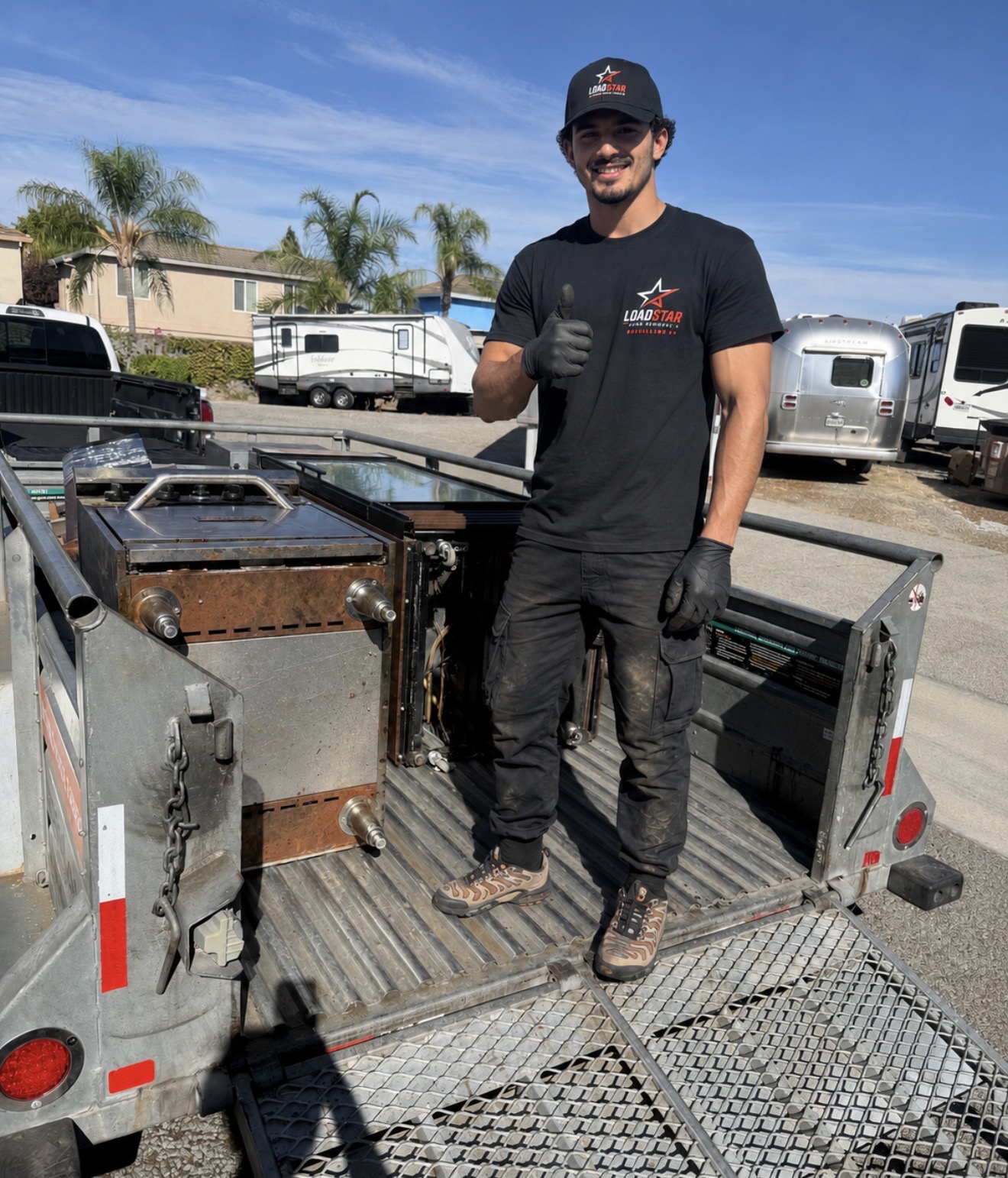 LoadStar crew member giving a thumbs up in a trailer loaded with appliances